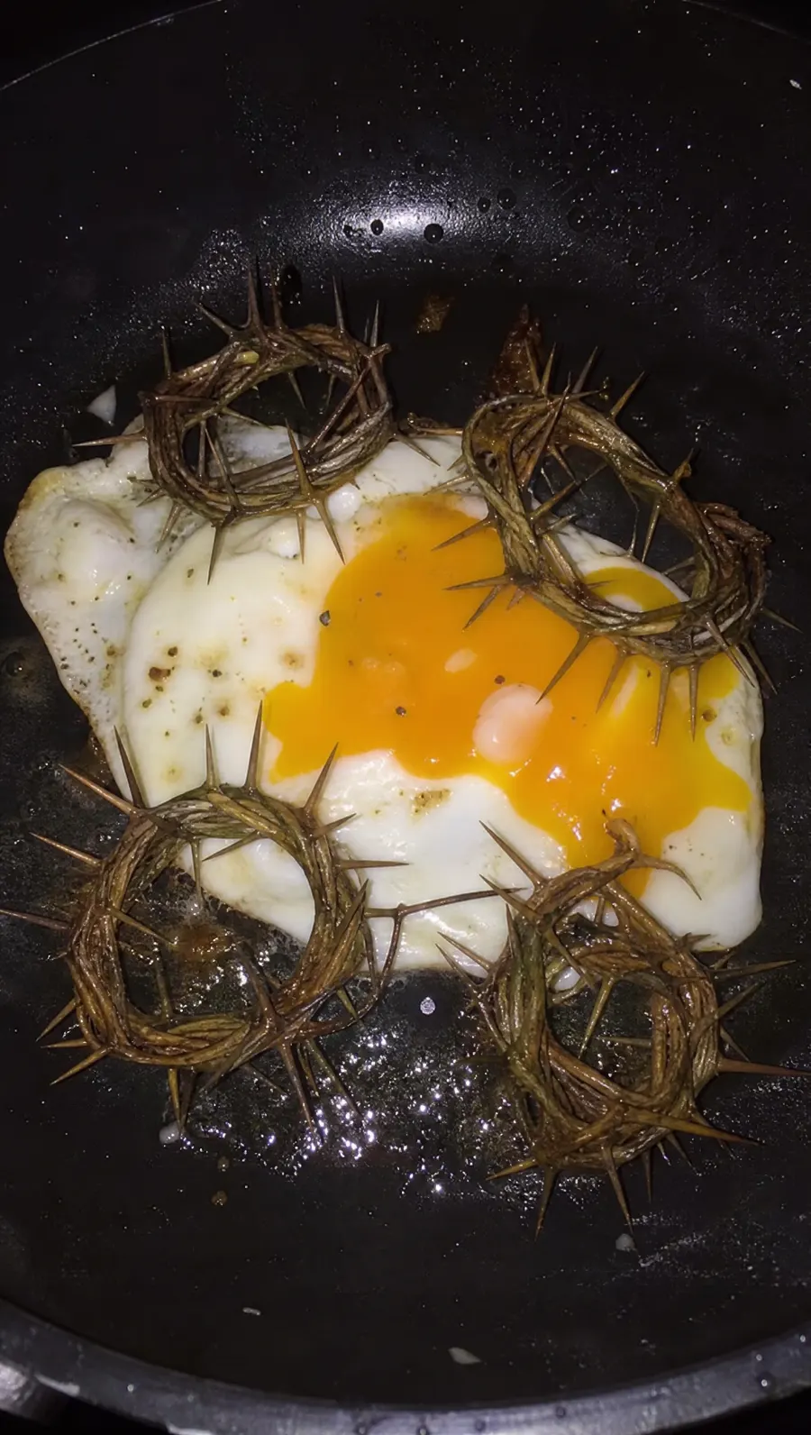 Huevos fritos en una sartén con coronas de espinas.